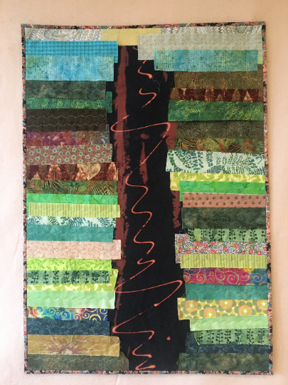 Green art quilt with brown river down the middle.